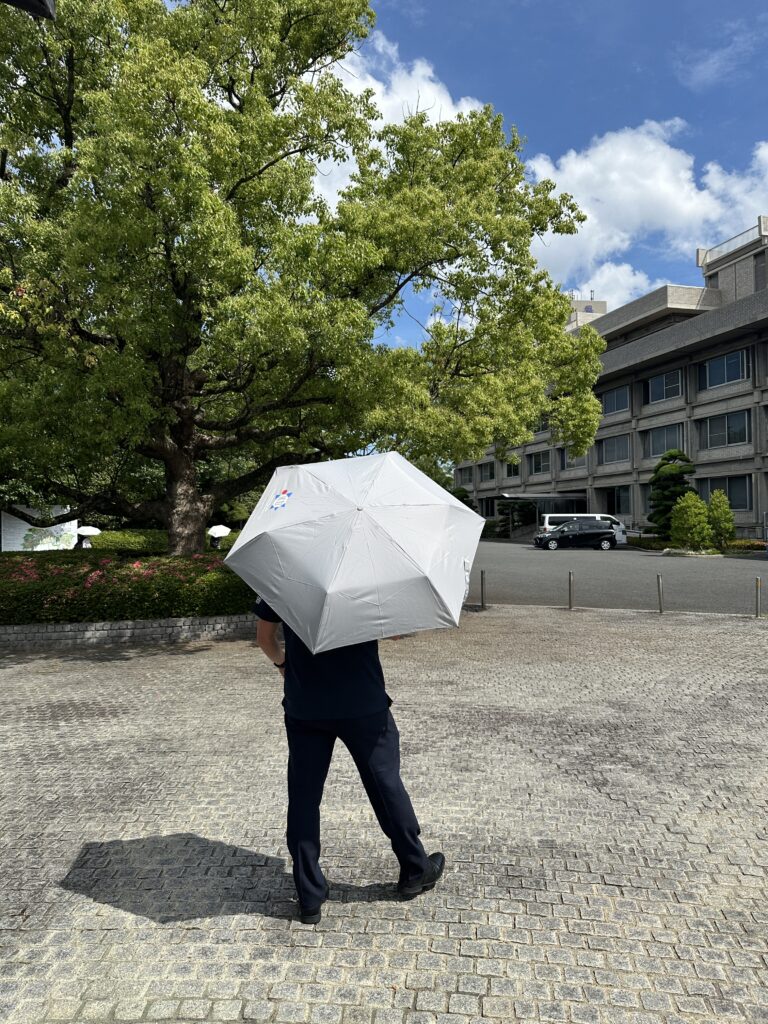 教育会館前を傘を持って歩く職員さんの写真。