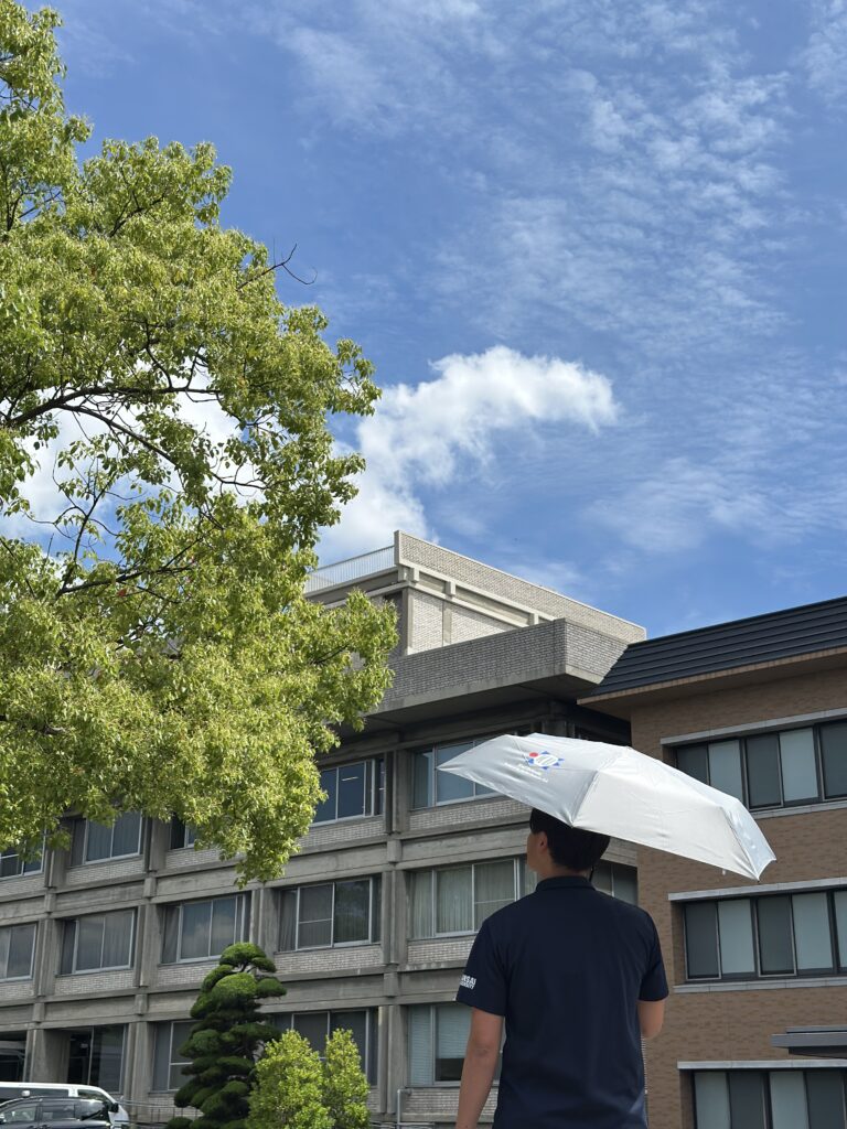 教育会館前を傘を持って歩く職員さんの写真２。
