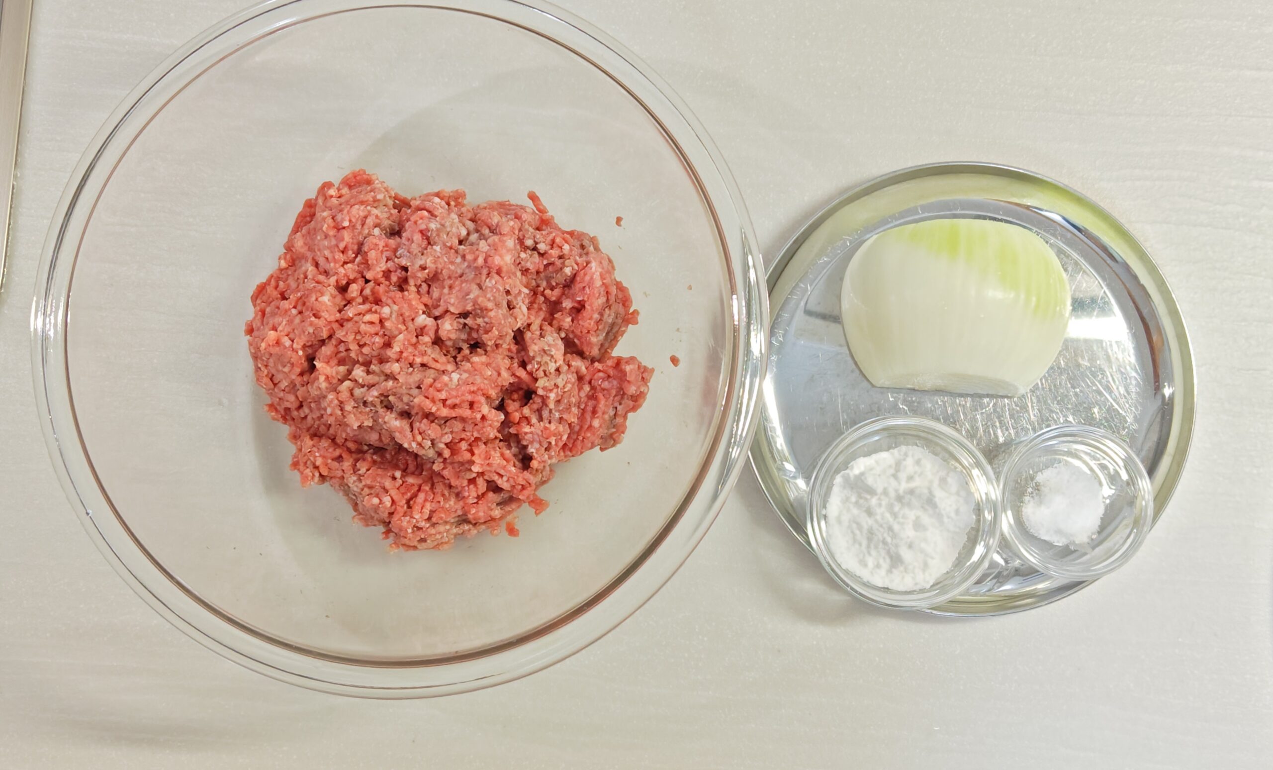 ミートボールの材料を並べた写真。ミンチ、たまねぎ、片栗粉、塩