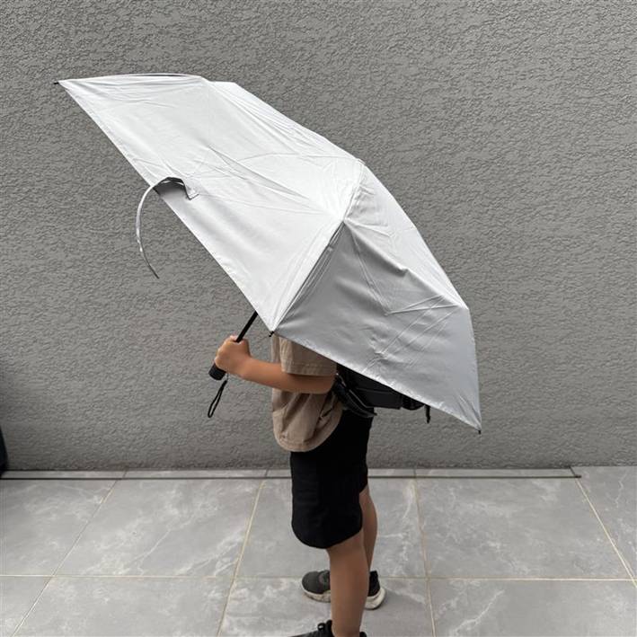 小学生の男の子がランドセルを背負って、傘を差している写真。ランドセルもスッポリおさまっている。