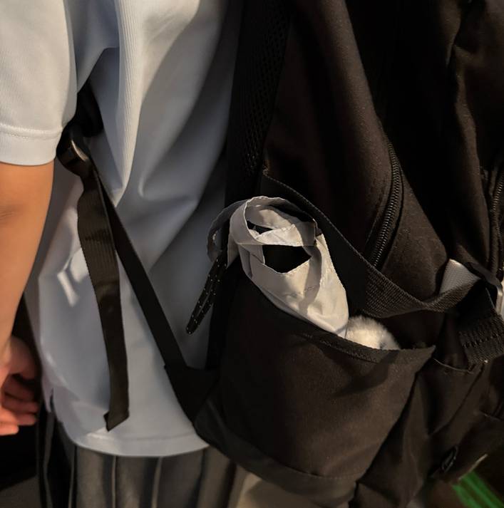 中学生の子供が背負っているリュックのサイドポケットに傘が入っている写真