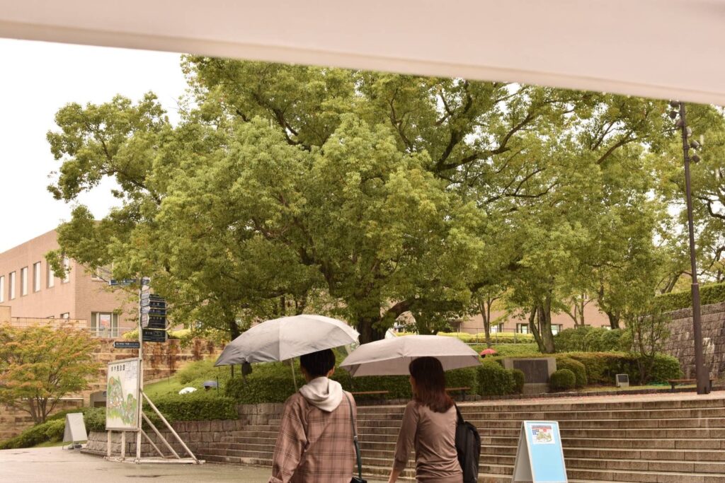 千里山キャンパス内で傘をさして歩いている女性と男性
