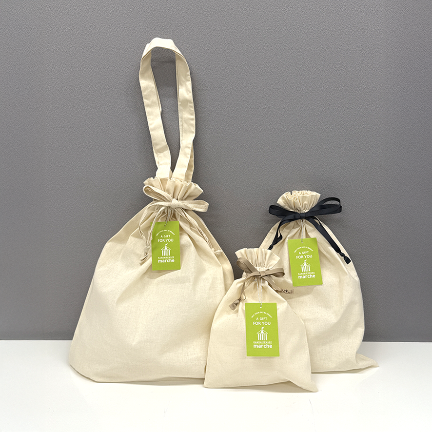 SMLサイズのコットン巾着袋（オリジナルタグ付き）が並んでいる写真。それぞれのサイズが分かりやすく見える。