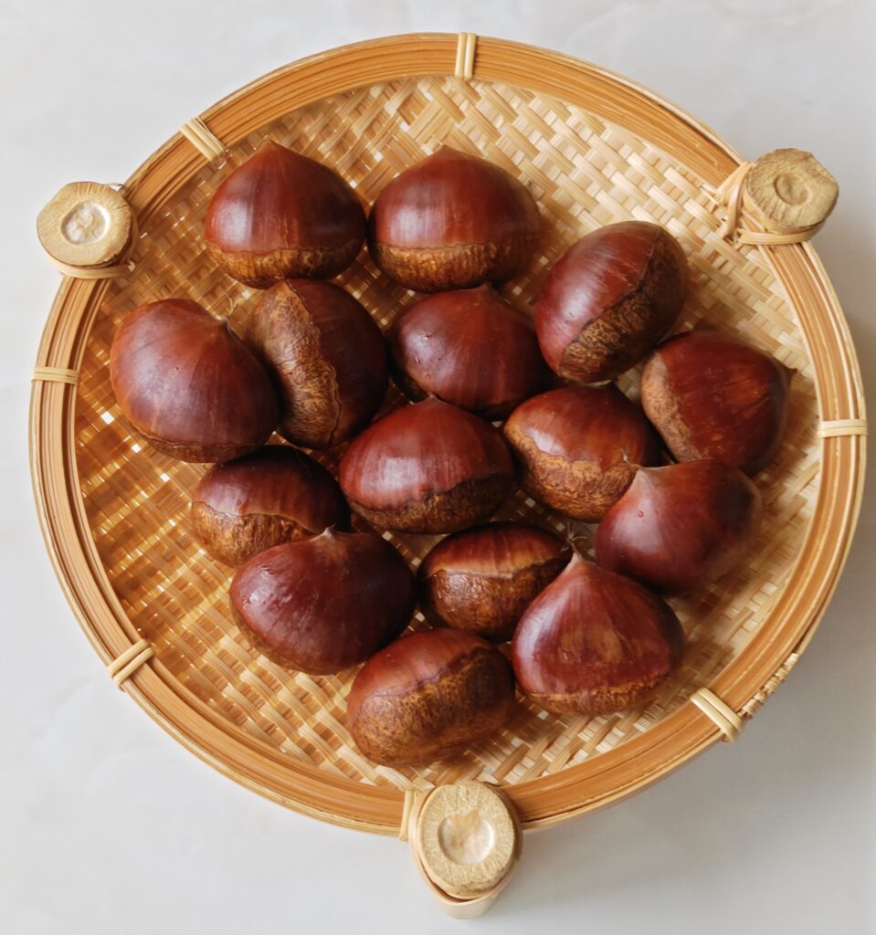 竹製のザルの上に、生栗をのせています。鬼皮をむく前で、表面がツヤツヤと輝いています。一枚目の写真よりも、少し遠めに撮影しています。