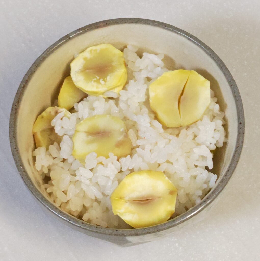 炊飯器に、お米、分量の水と塩、酒、出汁パックをいれて、その上に、鬼皮と渋皮が丁寧に剥かれて、一粒、半分~1/3にカットされた生栗を、まんべんなく広げてのせています。炊く前の状態です。