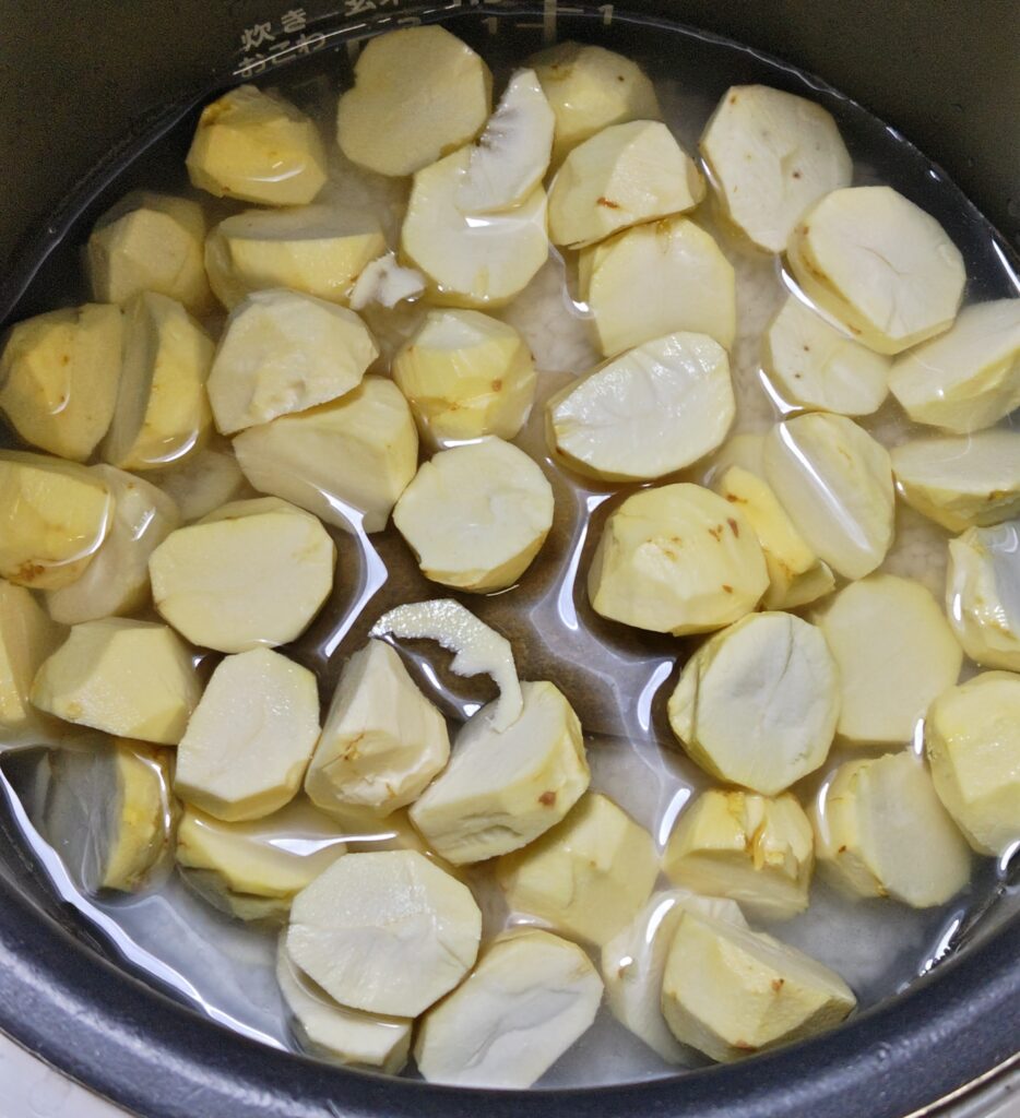 炊飯器に、お米、分量の水と塩、酒、出汁パックをいれて、その上に、鬼皮と渋皮が丁寧に剥かれて、一粒、半分~1/3にカットされた生栗を、まんべんなく広げてのせています。炊く前の状態です。