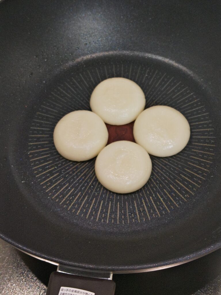 フライパンに丸もちを４つ並べています。丸もちは、地域特産「紅せんり」ブランド。丹波青垣産の滋賀羽二重もち使用「紅せんりのおもち」
