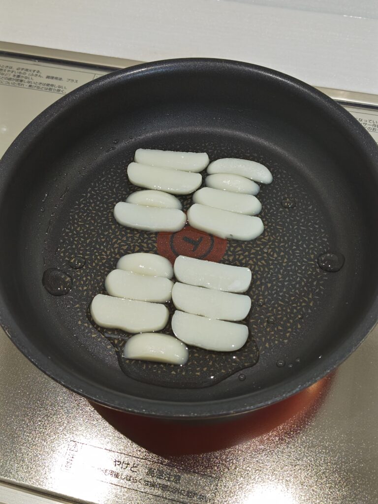 丸もちを７～８枚ほどにうすく切って、フライパンに並べ、水を加えた写真です。