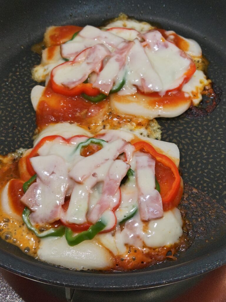 ピザソースをぬり、ベーコン、ピーマン、とろけるチーズをトッピングしたあと、フタをして蒸し焼きして仕上がりの写真です